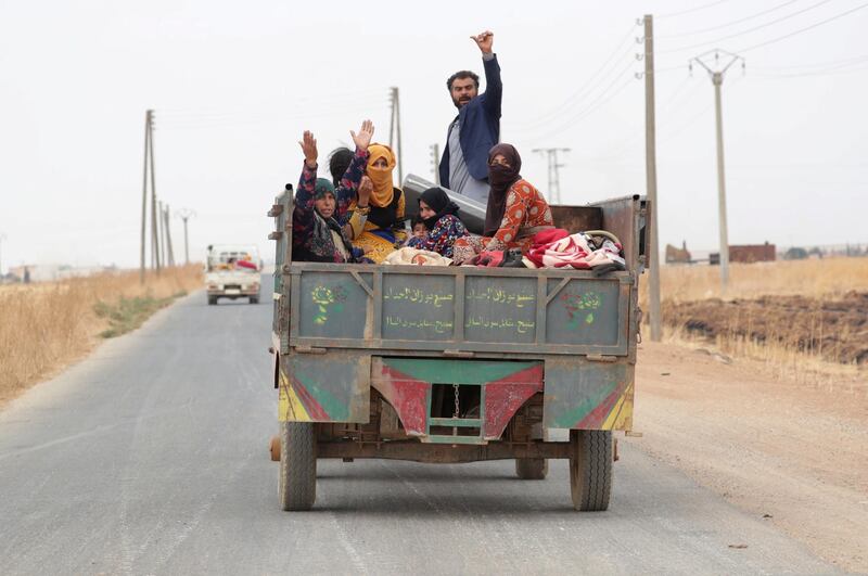 Civilians gesture while riding on a tractor as they withdraw from the border town of Tal Abyad, Syria. Reuters