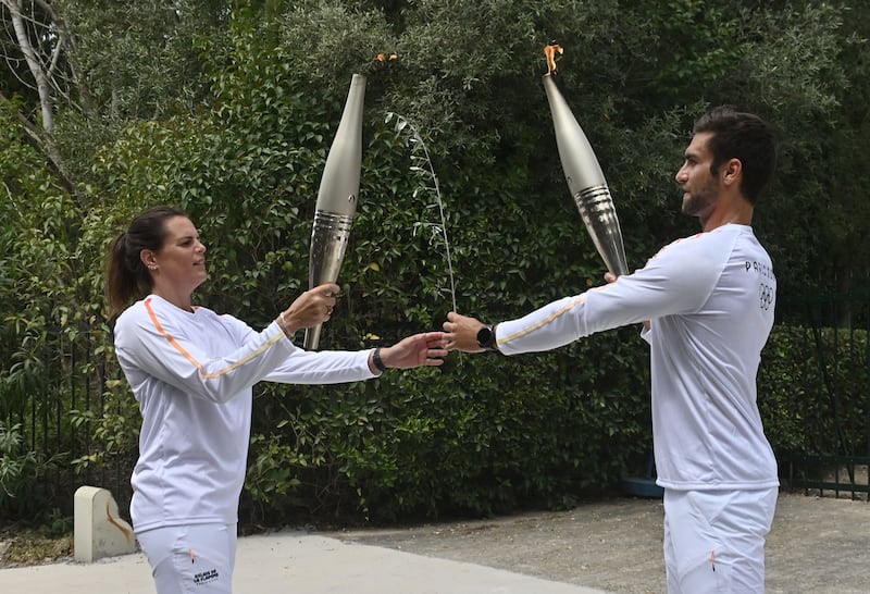 Ntouskos (right) lights the torch held by Second French Olympic swimmer, Laure Manaudou. AFP