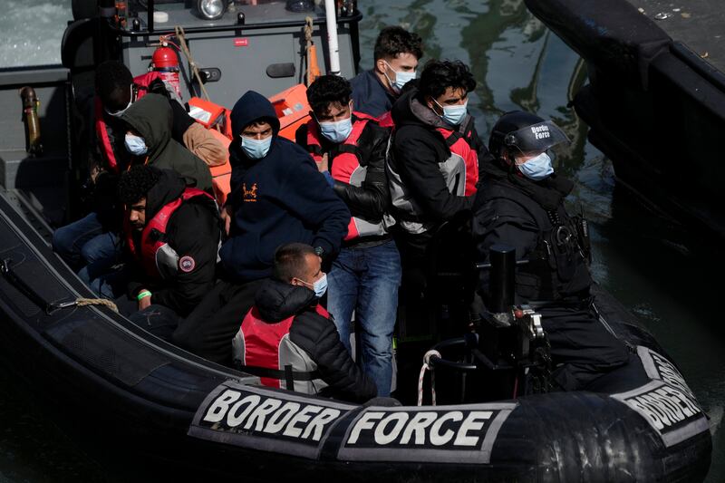 Migrants are taken off a small boat after arriving at England's southern tip from across the English Channel. AP