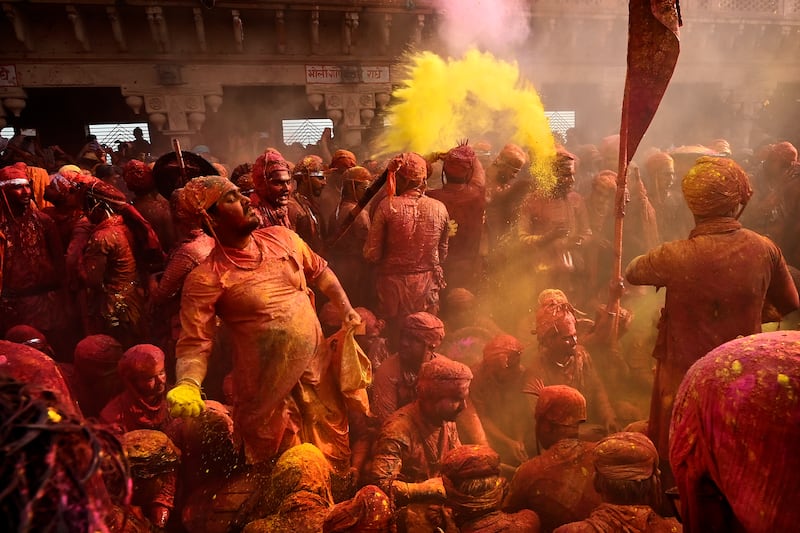 Men from Barsana village smeared with coloured powder at Nandagram temple, in Uttar Pradesh. Women playfully beat men with lathis (wooden sticks) as part of the ritual. AP