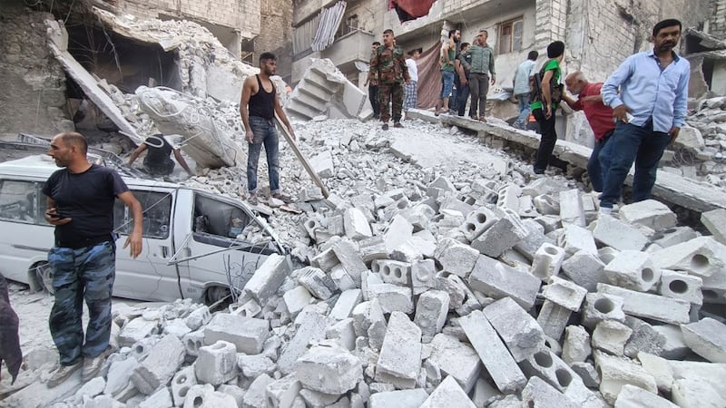 Syrian Civil Defense workers and civilians work on the rubble of a destroyed building, in Aleppo, Syria. AP