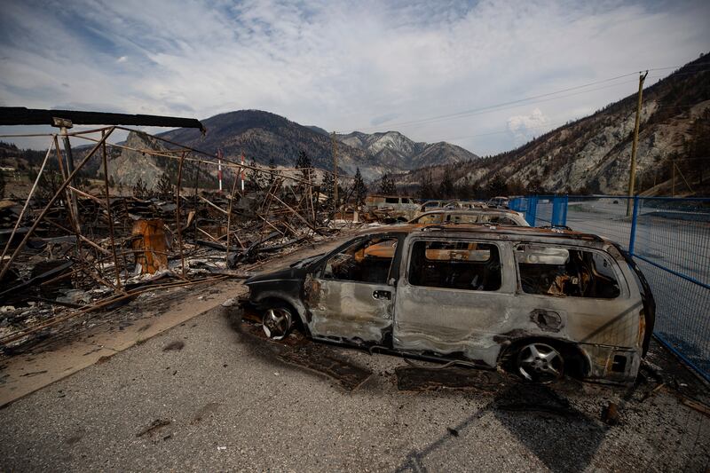 The remains of a large structure and vehicles destroyed by the Lytton Creek wildfire are seen on the side of the Trans-Canada Highway near Lytton, British Columbia.