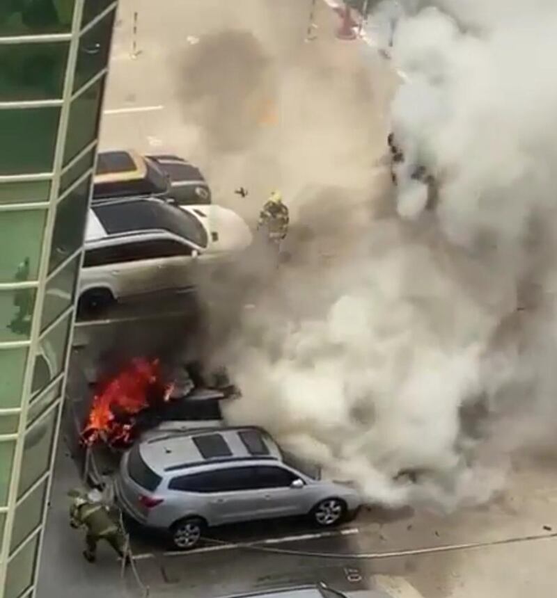 A firefighter takes cover as flames erupt from a vehicle in a Sharjah car park