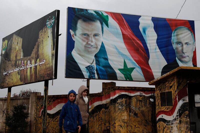 Syrian walk by posters of Syrian President Bashar Assad and Russian President Vladimir Putin in Aleppo, Syria, Thursday, Jan. 18, 2018. Syria said on Thursday its air defense would shoot down any Turkish jets that carry out attacks within Syria, a stark warning as tensions soar over apparent preparations by the Turkish military to invade a northern Syrian Kurdish enclave. Arabic on the left read, "Aleppo is your city and you need to defend it." (AP Photo/Hassan Ammar)