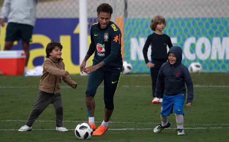 Brazil's player Neymar (C) plays with his son David Lucca (R) and other children after a training session of the national football team ahead of the FIFA 2018 World Cup, at Granja Comary training centre in Teresopolis, Rio de Janeiro, Brazil, on May 25, 2018. / AFP / Mauro PIMENTEL
