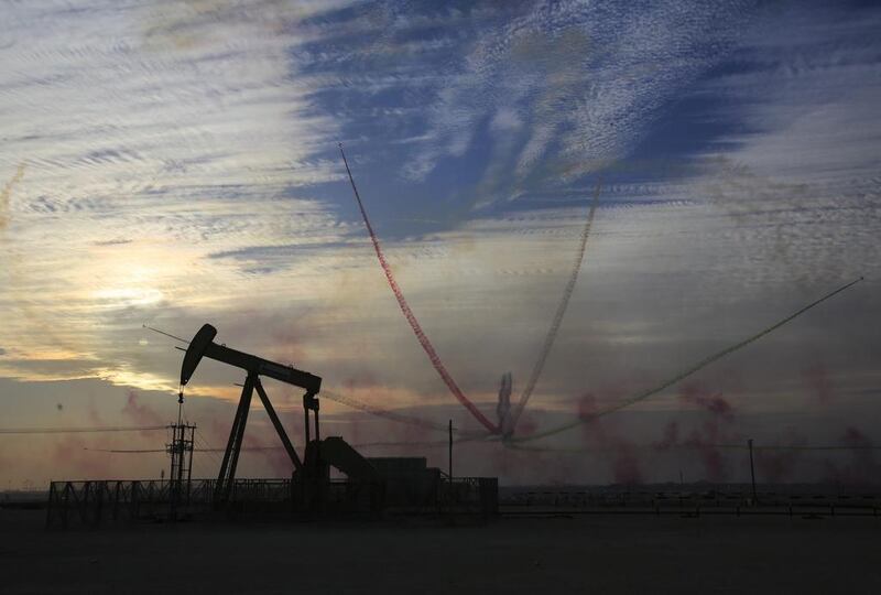 An oil pump works as Al Fursan, the aerobatics demonstration team of the UAE Air Force, performs during the Bahrain International Airshow in Sakhir, Bahrain. Hasan Jamali / AP Photo