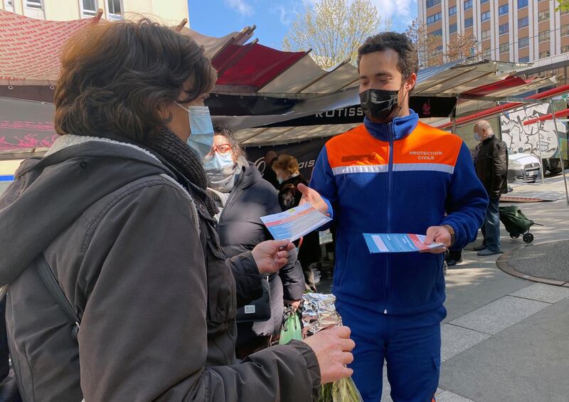 Volunteers from French Protection Civile association hand out leaflets at a market to try to persuade Parisians over 55 to have the AstraZeneca vaccine, in Paris, France. Reuters
