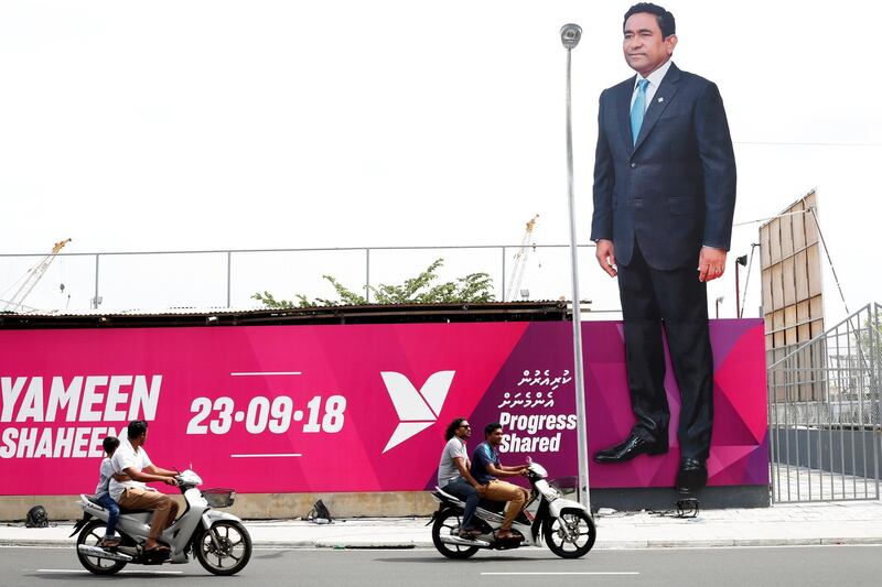 People ride motorcycles past a giant image of Maldives President Abdulla Yameen in Male. Ashwa Faheem / Reuters