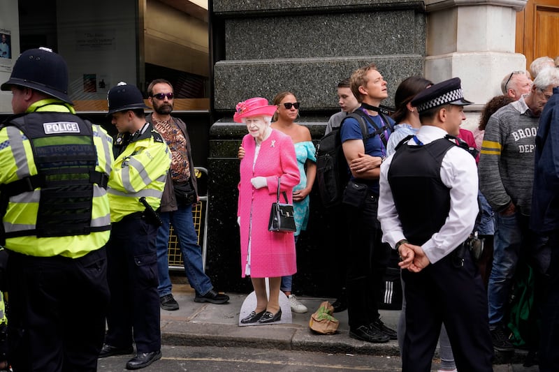 A woman holds a cutout of Queen Elizabeth II outside St Paul's Cathedral. AP