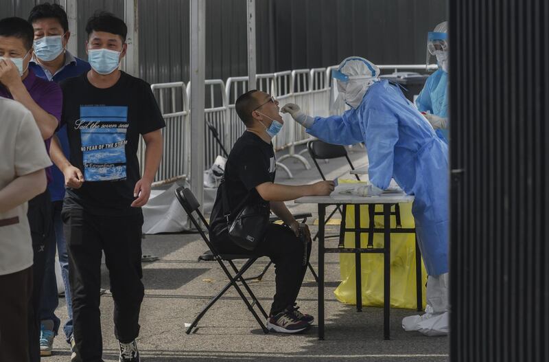 BEIJING, CHINA - JULY 01: A Chinese epidemic control worker wears a protective suit as she performs a nucleic acid swab test for COVID-19 on a man at a government testing site on July 1, 2020 in Beijing, China. While Chinese government medical officials have said they believe they have contianed the outbreak, authorities are trying to control the spread of COVID-19 infections linked to the Xinfadi wholesale food market, Beijing's biggest supplier of produce and meat. More than 8 million people have undergone nucleic acid tests for COVID-19 at dozens of sites across the city in recent days, with officials using contact tracing to target high and middle risk areas and people who may have had contact with the market or food that came from there. Several neighborhoods have been locked down and a number of other food markets have been closed. (Photo by Kevin Frayer/Getty Images)