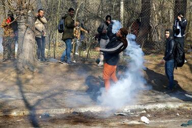 A migrant throws a tear gas canister back during clashes with Greek police in February at the border near Greece's Kastanies. Reuters