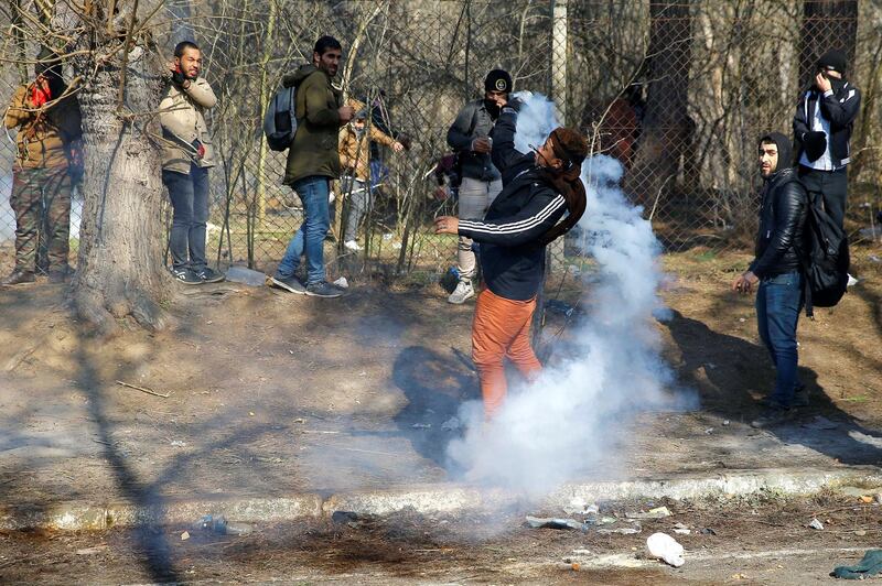 A migrant throws a tear gas canister back during clashes with Greek police, at the Turkey's Pazarkule border crossing with Greece's Kastanies, in Edirne, Turkey, February 29, 2020. REUTERS/Huseyin Aldemir