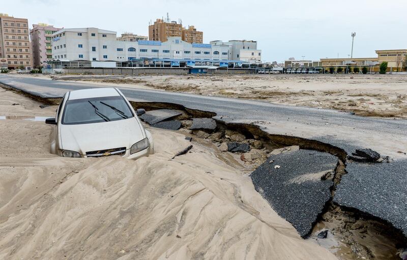 A car is swept away on a damaged road following heavy rain in Kuwait City. EPA