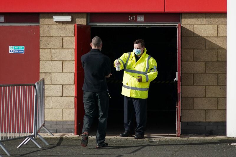 A member of security sprays hand sanitiser for a patient as they arrive at the Riverside Stadium Vaccination Centre in Middlesbrough. Getty Images