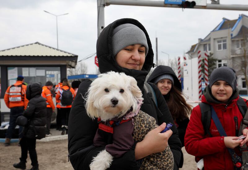 A woman carries a pet dog as people who fled Ukraine walks through the border checkpoint near the Moldovan town of Palanca.  AFP