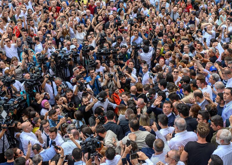 Ekrem Imamoglu, right, waves as he leaves after casting his vote in what has become a test of Turkish democracy as well as the Turkish President's continued popularity at a time of economic trouble. AFP / Bulent Kilic