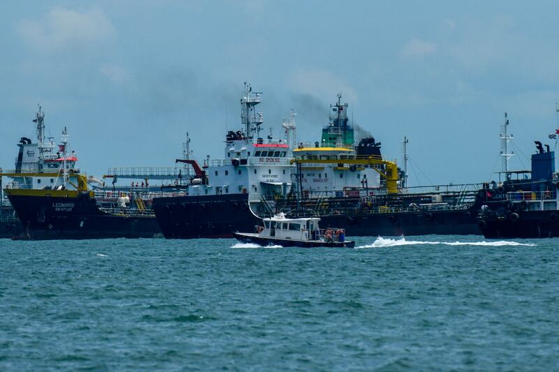 A boat sails past oil tankers anchored along the East Coast waterway in Singapore. Oil demand is likely to reach pre-pandemic levels of 100 million bpd as early as December, according to UBS. AFP