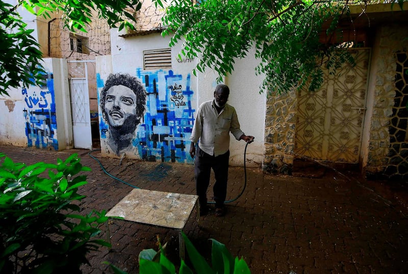 Sudanese Kisha Abdulsalam waters plants near a mural depicting his late son Abdulsalam in Khartoum on the eve of a raid where at least 128 people were killed and hundreds wounded outside Khartoum's army headquarters. AFP