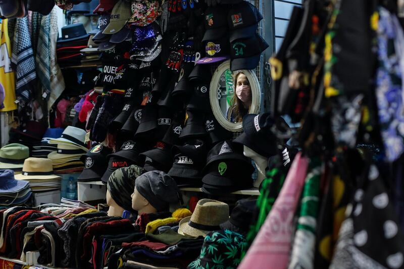 A woman wearing a mask to curb the coronavirus is reflected on a mirror of a shop in Monastiraki district of Athens. Greece's government will impose from Saturday a nightly curfew in greater Athens and other areas with high infection rates. AP