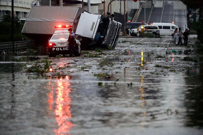 A police officer stands beside a flooded road following a powerful typhoon in Osaka, western Japan. Kyodo News via AP