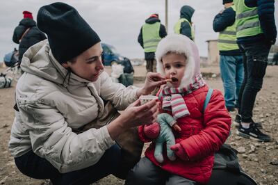 Lena Ivanenko, who had never left Ukraine before fleeing into Moldova, feeds daughter Dasha, 3, at a refugee resting point just over the border. Erin Clare Brown / The National