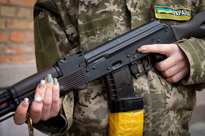 An armed civil defence woman holds a Kalashnikov assault rifle while patrolling an empty street in Kiev. AP