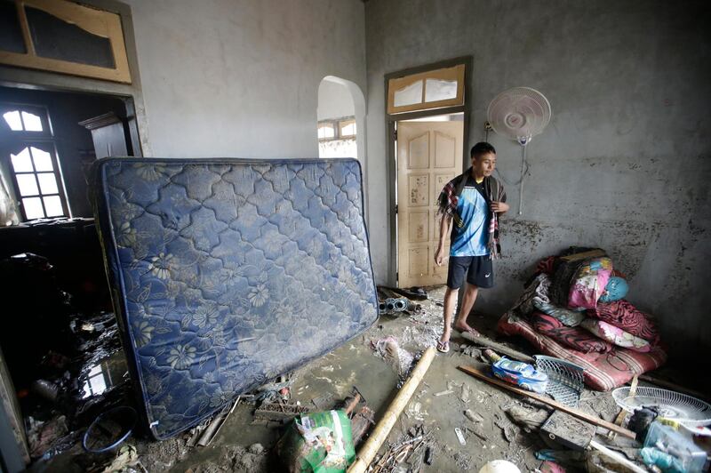 A survivor walks inside a vavaged house in Sumur. AP Photo