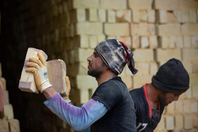 Workers stack bricks at the factory.  AFP