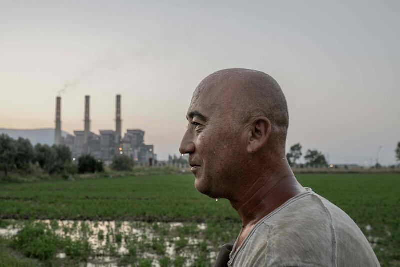 Turkish villager Okan Goktas, 44, cools off using the water irrigating his field close to the coal-powered Yatagan power plant