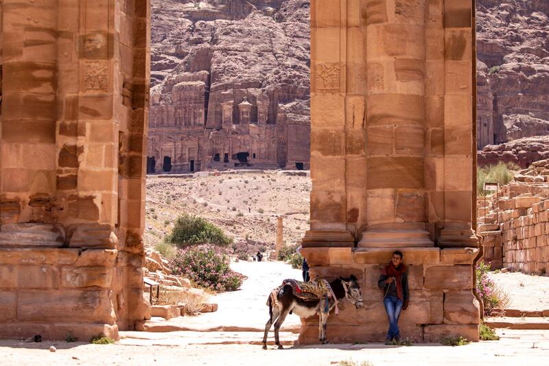 A man stands in the shade with his donkey at the reopened Petra archeological site. EPA