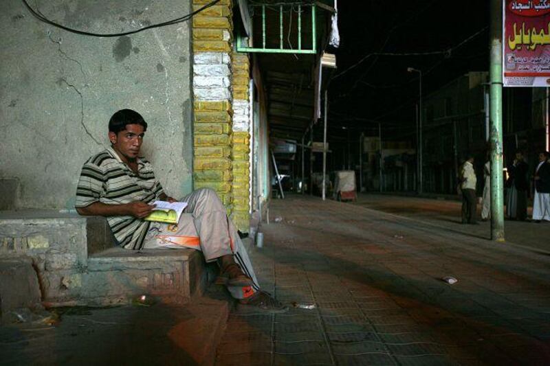 A young Iraqi studies in light from a diesel generator during a power blackout in Babil province.