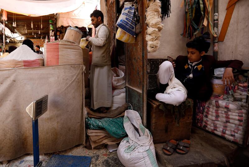 A Yemeni boy uses a smartphone as a vendor sells flour at a market in Sanaa, Yemen. EPA