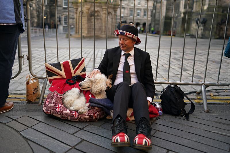 A man with his dog arrive early as they wait to view the cortege carrying the coffin of Queen Elizabeth in Edinburgh. Getty Images