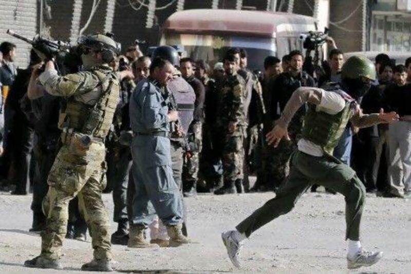 A Nato soldier, left, stands guard at the scene of an attack by Taliban militants in Kabul on Sunday.