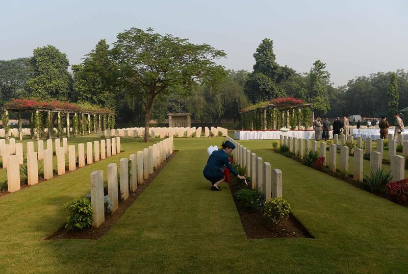 An Indian army officer puts flags next to a tombstone at Delhi War Cemetery in New Delhi. AFP