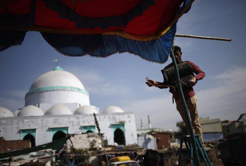 A Muslim man uninstalls a light from a temporary tent in front of a mosque.