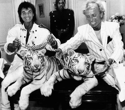 FILE - In this June 4, 1987, file photo, Las Vegas magicians Roy Horn, left, and Siegfried Fischbacher pose in New York, with their rare white tigers, Neva, left, a female, and Vegas, a male, during a stop at Van Cleef & Arpels jewelry before their departure for Germany. Horn, one half of the longtime Las Vegas illusionist duo Siegfried & Roy, died of complications from the coronavirus, Friday, May 8, 2020. He was 75. (AP Photo/Scott McKiernan, File)