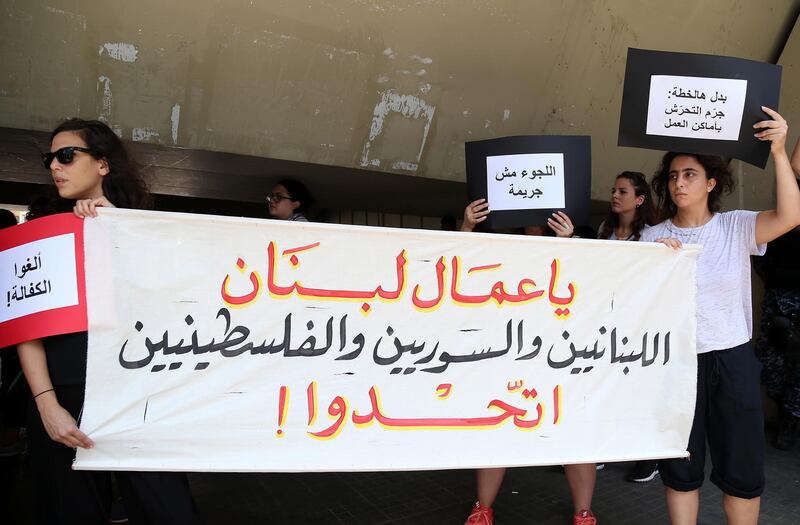 epa07747395 Protesters hold a banner reading in Arabic 'to all Lebanese workers, including Lebanese, Syrians and Palestinians, unite' during a protest against the Lebanese labor minister in front the Labor Ministry in the southern suburb of Beirut, Lebanon, 29 July 2019. According to reports, activists are protesting against the raids and arrests by the Ministry of Labor targeting unlicensed foreign workers, and calling for the abolition of the requirement to obtain a work permit for refugees.  EPA/NABIL MOUNZER