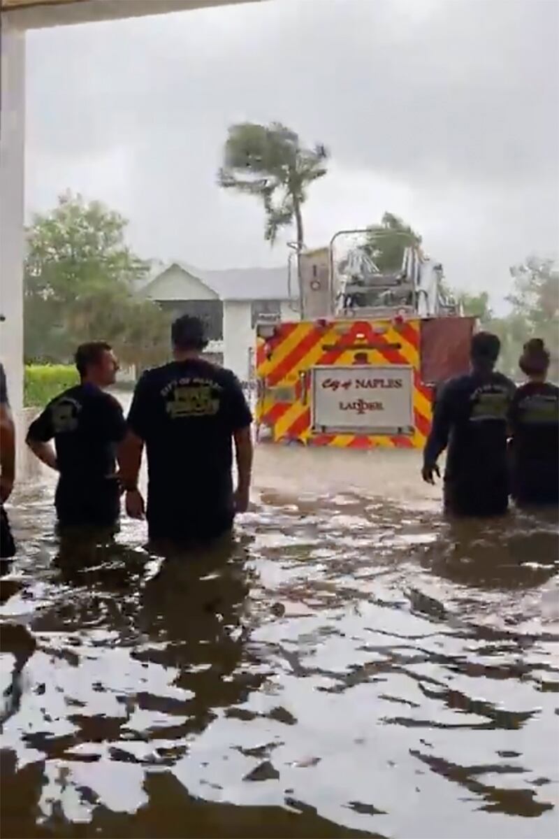 Firefighters in Naples, Florida look out at their fire engine standing in water. AP
