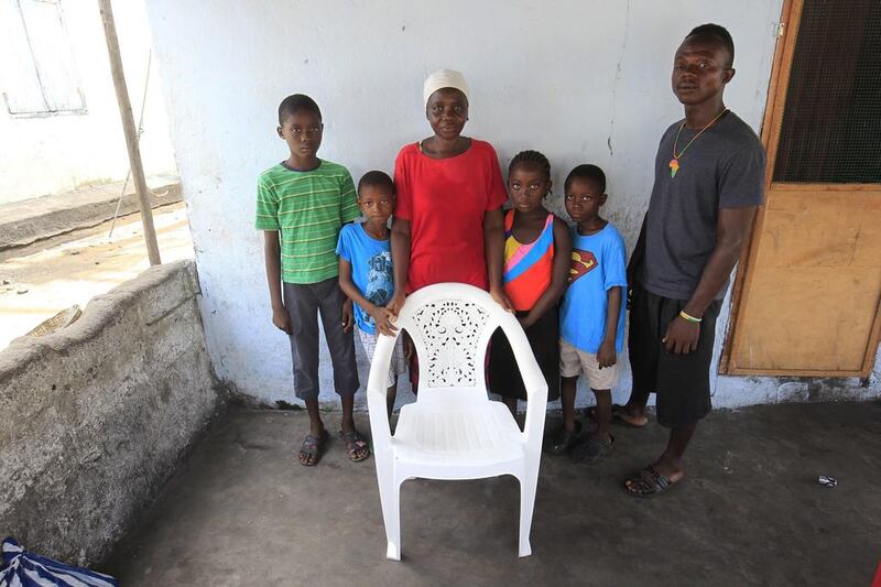 Yata Sesay, centre, with her children Sidikie, Siafa, Haja, Foday and Foday pose for a family portrait at their home in West Point, Monrovia, Liberia. The empty chair is a representation of Yata’s husband, Mohammed Sesay, who died of the Ebola virus disease.  Ahmed Jallanzo / EPA