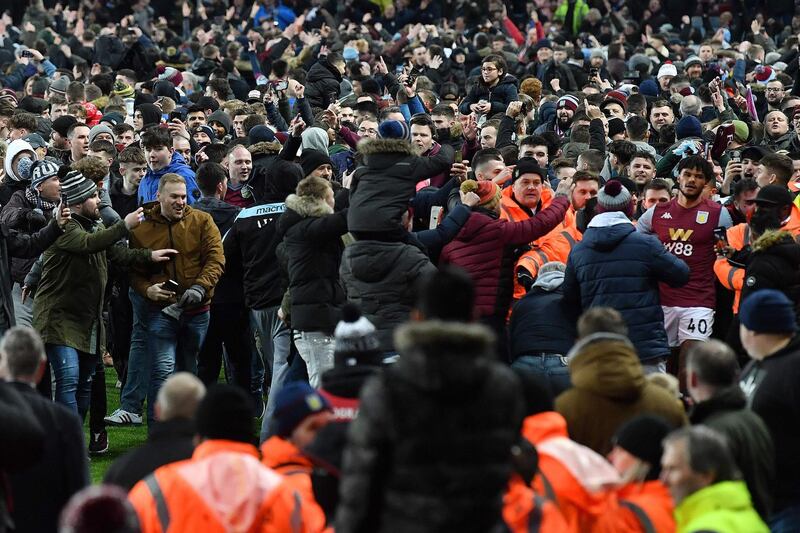 Tyrone Mings tries to leave the pitch after Aston Villa fans celebrate on the pitch. AFP