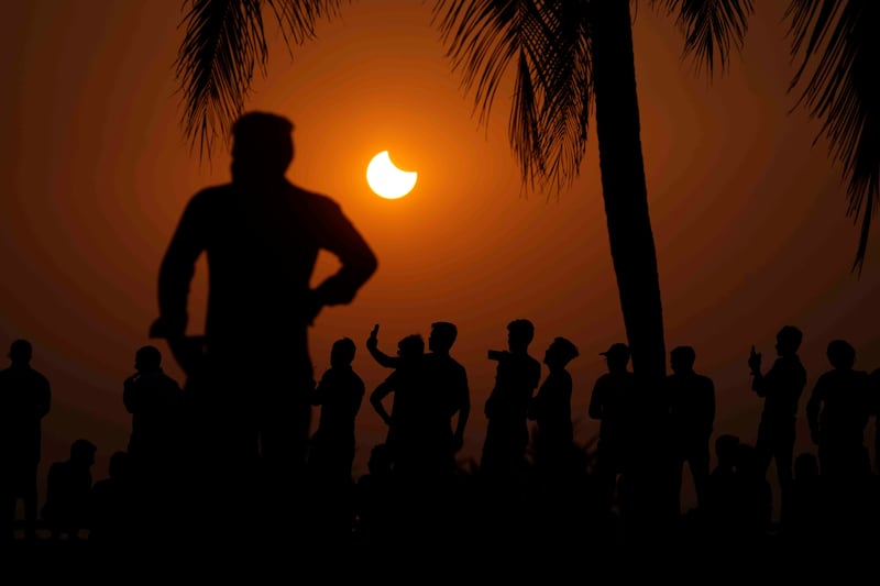 People watch a partial solar eclipse in Mumbai, India. AP