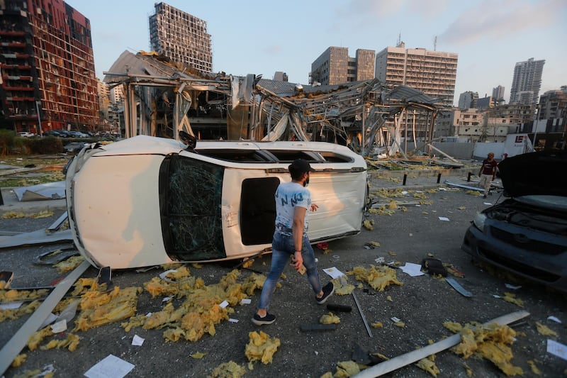 A man walks by an overturned car and destroyed buildings. Getty Images