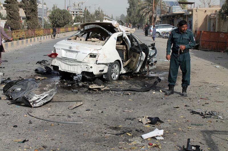 An Afghan policeman investigates a damaged car following a sticky bomb attack in Helmand province, southern Afghanistan, Thursday, Nov. 12, 2020. A bomb attached to the vehicle of a radio journalist in southern Afghanistan exploded early Thursday, killing him, a provincial official said. (AP Photo/Abdul Khaliq)