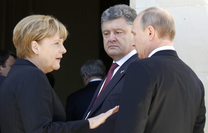 The German chancellor Angela Merkel talks to Russian president Vladimir Putin, right, as Ukraine’s president-elect Petro Poroshenko looks on after a group photo for the 70th anniversary of the D-Day landings at Benouville Castle, France, on June 6, 2014. Regis Duvignau / Reuters