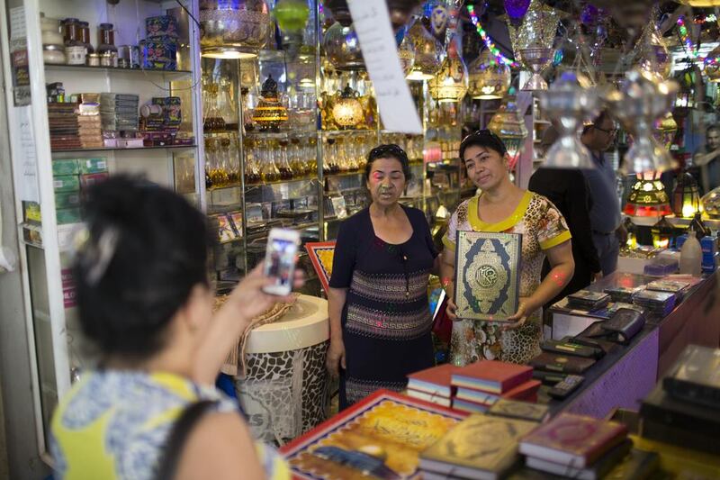 A tourist taking a photo and holding a Quran  in the old market during the holy month of Ramadan in the Old City of Jerusalem.