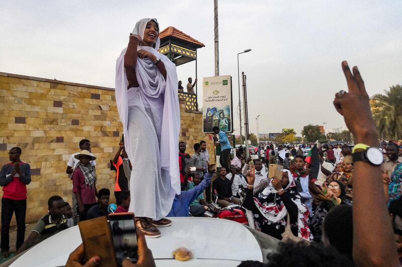 (FILES) In this file photograph taken on April 10, 2019, Alaa Salah, a Sudanese woman propelled to internet fame earlier this week after clips went viral of her leading powerful protest chants against President Omar al-Bashir, addresses protesters during a demonstration in front of the military headquarters in the capital Khartoum. Draped in white and addressing the crowd from the roof of a car, Alaa Salah has become one of the icons of the Sudanese revolution and the voice of women in her country. Its appearance has earned it the nickname "Kandaka", or "the Nubian Queen", in reference to the rulers who marked the region's history in antiquity.
 / AFP / -
