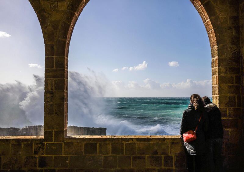 People watch waves crash by the historical Phoenician Wall in the coastal northern Lebanese town of Batroun. AFP