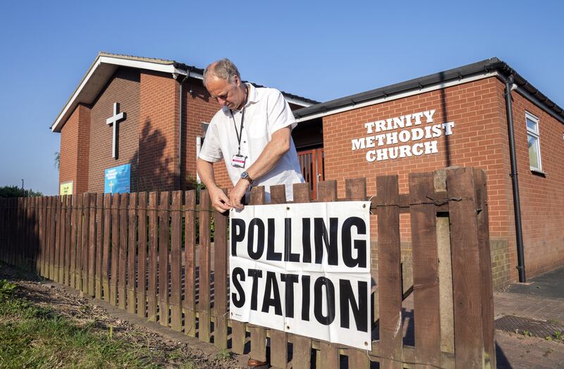 Presiding officer David Farringdon adjusts a polling station sign near Trinity Methodist Church in Wakefield, England, as voters cast their votes in the by-election, which was triggered by the resignation of Imran Ahmad Khan. PA