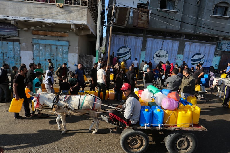Palestinians line to collect water in Rafah on Saturday, November 18. AP